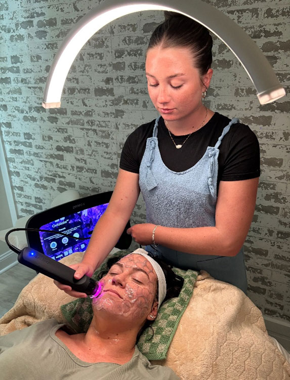 two women, one providing the Glo2 treatment, the other being treated.